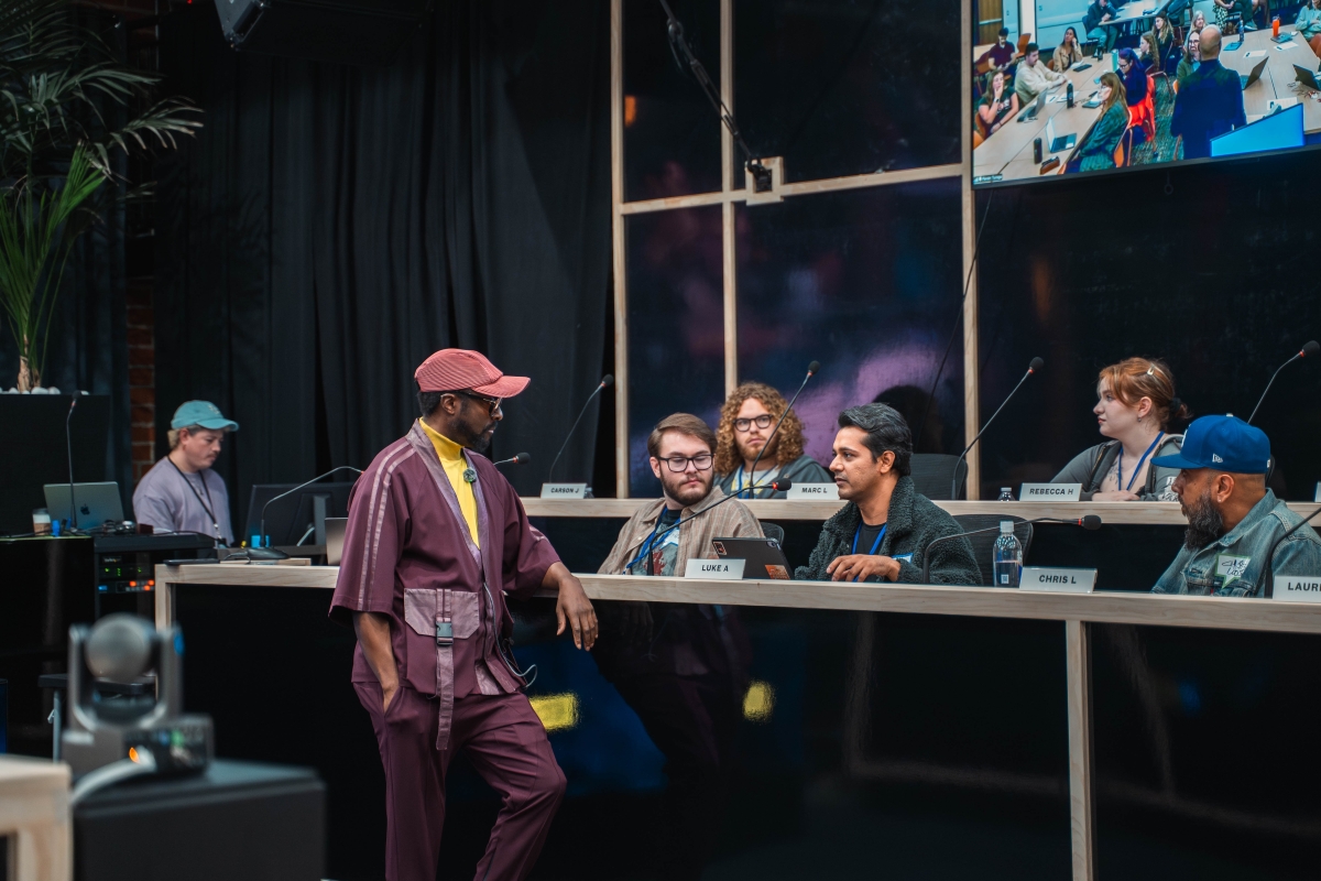 will.i.am stands as he talks with students